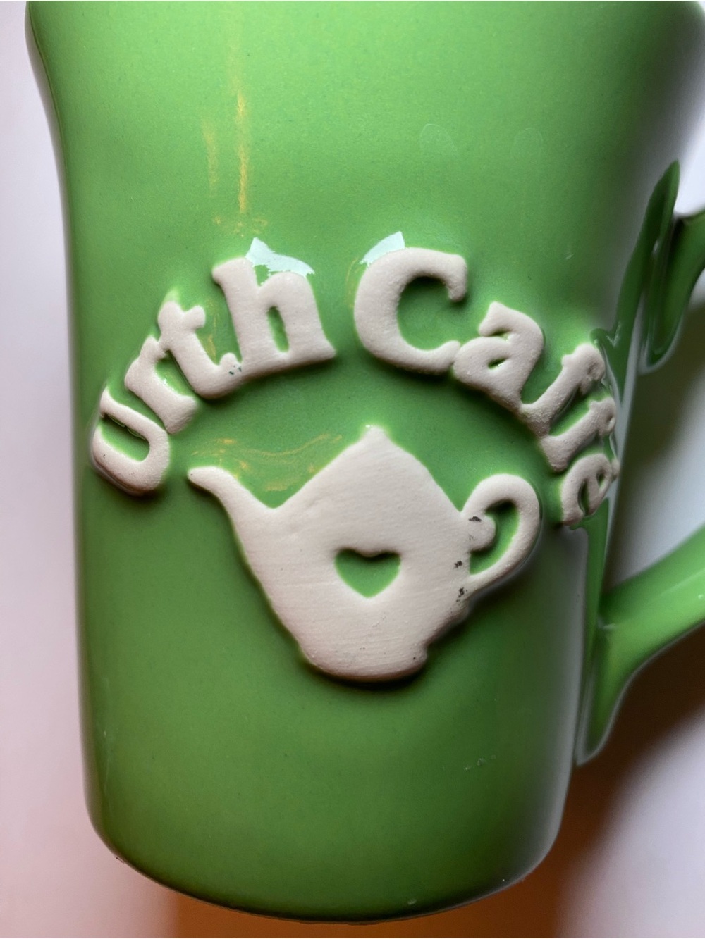 Urth Cafe ceramic coffee mug in green with white embossed logo